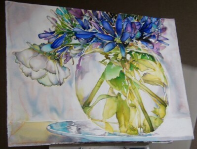 A mixture of blue, purple, and white flowers in a clear bowl vase